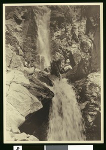 Woman next to a waterfall on a trail to the summit of San Gorgonio, 1900-1915