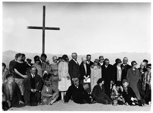 Men and women in front of a cross for a funeral in the desert