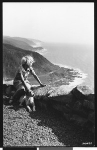 Girl and dog looking South along the Pacific coast from Cape Perpetua in the Siuslaw National Forest, Oregon, August 1935