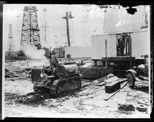 Two men operating a tractor at an industrial site