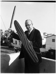 Man holding a wooden shield and stick at the Pacific Southwest Museum