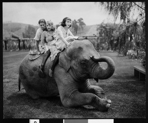 Three woman acting as children on top an elephant, ca. 1920-1929