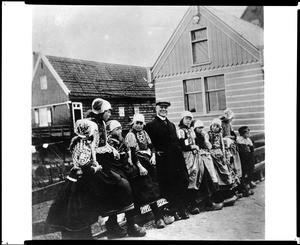 Sunset Club member in Holland with several young Dutch girls in traditional costumes, ca.1910