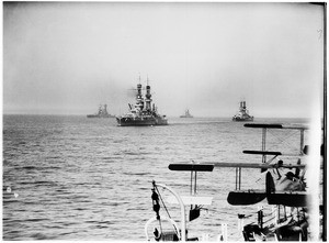 View of four battleships at sea from the deck of another ship