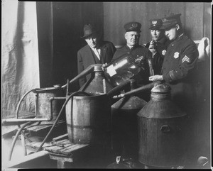 View of police investigating an illegal still, showing distillery equipment, ca.1920-1929