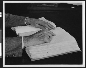 Hands "reading" a Braille book, ca.1928