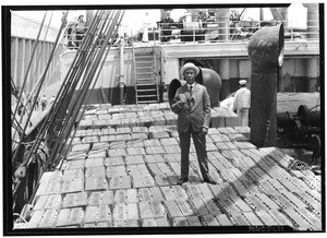 William Lacy standing on orange crates from Hawaii on a ship, ca.1930