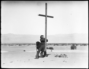 Two men digging around a cross for a funeral in the desert