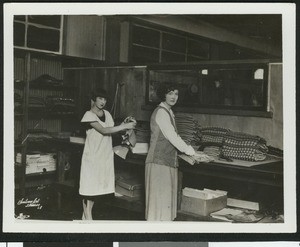 Two women folding garments in a Los Angeles clothing factory, ca.1928