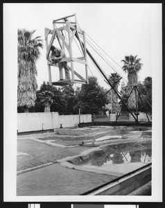 Man photographing a model waterway system from an elevated platform, ca.1925