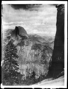 View from "Short Trail" of Half Dome and two people standing on the precarious Glacier Point in Yosemite National Park, 1900-1902