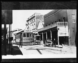 View of a street in Grass Valley, showing a cable car and the exterior of a grocery store, ca.1910