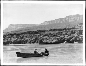 Three men and a dog in a rowboat crossing the upper Colorado River at Lee's Ferry, Grand Canyon, 1900-1930