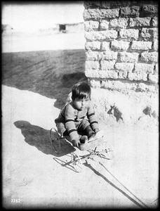 Small Pima Indian boy playing in a child's wagon, Gila Crossing, ca.1900