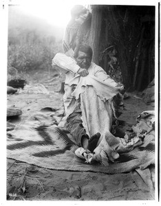 Havasupai Indian man dressing a deer hide, ca.1900