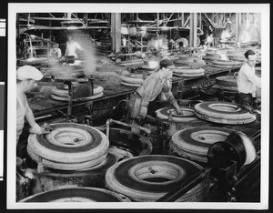 Factory workers loading and unloading molds in a tire factory, ca.1930