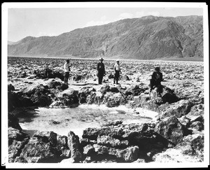 Four people standing near a salt pool in Death Valley, ca.1900-1950