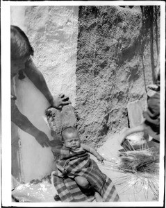 Hopi Indian baby laying outside, ca.1900