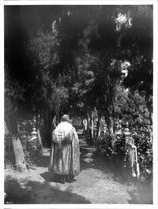 Father Reposo walking in the cemetery at Mission San Jose, ca.1900