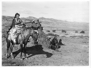 View of a Navajo Indian maiden on a pony in front of a hogan, ca.1901