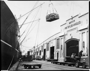 Exterior view of Berth 179 of the Los Angeles Harbor, showing a ship and cargo, ca.1960