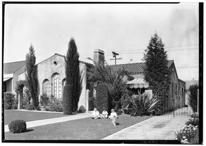 Children playing with a dog on the front lawn of a house in Los Angeles