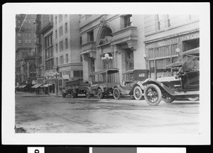 Automobiles and trucks parked on an unidentified city street, ca.1920