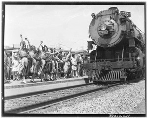 Women holding baskets of fruit next to a train