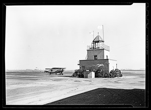 View of an air-traffic control tower with a bi-plane nearby