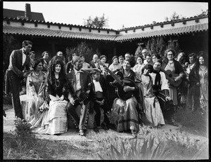 Group of Mexicans at a party posed on a fountain listening to a guitar player