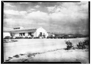 Exterior view of a lightly-colored building, showing hills in the background