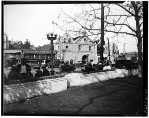 People sitting along a wall across from the Plaza Church in Los Angeles