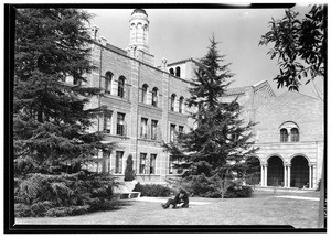 Man sitting on a lawn in front of an unidentified building at the University of California at Los Angeles, February 1938