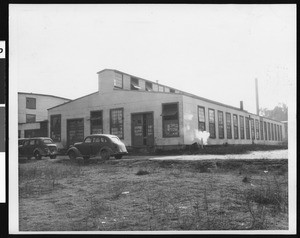 Exterior of the Pacific Portland Cement Company's Plaster City Plant, showing automobiles in foreground, ca.1935