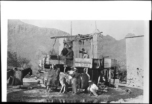 Men and burros laboring at a "Mexican Water System" around what may be a large well, ca.1920