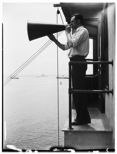 Man with a bull horn standing outside the Marine Exchange in San Pedro