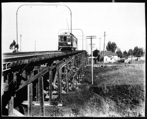 View of a Pasadena electric trolley car on elevated tracks over the Southern Pacific Railroad Company tracks at Alhambra Avenue, 1908