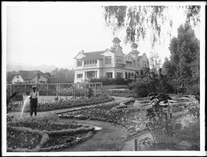 Gardener watering the garden at the Hollywood residence of Paul deLongpre, Hollywood Boulevard and Cahuenga Avenue, ca.1902-1903