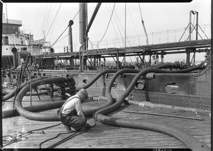Man adjusting hoses on the Standard Oil Company dock, San Pedro, ca.1920