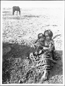 Mojave Indian woman sitting with her grandchild on the ground, ca.1900