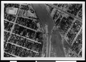 Aerial view of unidentified flooded area, showing damaged buildings and roadways, 1938