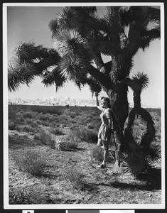 Woman leaning against a Yucca tree