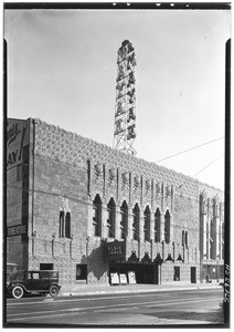 Exterior view of the facade of the Mayan Theater, showing a scaffold sign tower on top, ca.1925