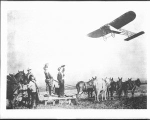 Bleriot monoplane passing over a group of farmers and mules, June 1910