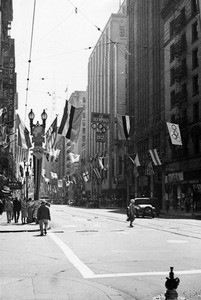 View of the intersection of Fourth Street and Spring Street in Los Angeles, showing decorations for the Olympics, 1932