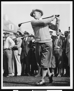 Golf player Mac Donald Smith on a golf course, with a crowd behind, 1928