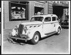 View of a 1935 DeSoto taxi parked at the employees entrance of Haines Department Store and Star Drug Company, ca.1935