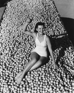 Portrait of a woman in a bathing suit sitting in a truck full of oranges