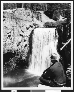 Man seen from behind, sitting on a cliff near a Rainbow Falls near the San Joaquin River, ca.1950