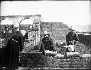 Father O'Keefe directing the work of two Neophytes at work on the rebuilding of Mission San Luis Rey de Francia, California, 1904